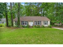 Charming single-story home with a well-manicured lawn, surrounded by lush trees at 116 Runnymede Ln, Summerville, SC 29485