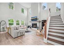 Bright living room boasts a fireplace, large windows, hardwood floors, and a staircase at 1387 Thin Pine Dr, Johns Island, SC 29455