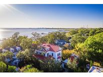 Stunning aerial view of a white multi-story home with a red roof near the coast and green trees at 202 Bank St, Mount Pleasant, SC 29464