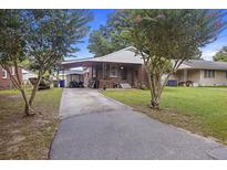 Charming brick home with covered parking, a well-kept lawn, and mature trees at 2703 Phyllis St, North Charleston, SC 29405
