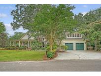 Charming home with a covered porch, mature trees, and a two-car garage with green doors at 312 Hobcaw Dr, Mount Pleasant, SC 29464