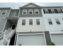 Townhome exterior with a white garage door, various toned sidings, and a staircase leading to the front door at 313 Lanyard St, Johns Island, SC 29455