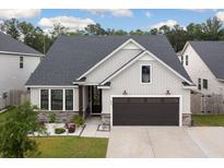 Charming single-Gathering home featuring stone accents, a dark two-car garage, and manicured landscaping at 404 Omaha Dr, Moncks Corner, SC 29461