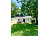Charming white brick home featuring an attached garage, mature trees, and a well-manicured lawn at 1015 Jacksnipe Ln, Mount Pleasant, SC 29464