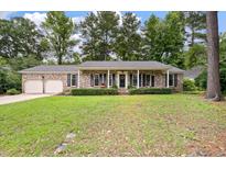 Charming brick ranch-style home with a welcoming front porch, manicured lawn, and lush landscaping at 109 Lakeview Dr, Summerville, SC 29485