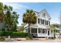 Charming two-story home with white siding, black shutters, and lush palm trees, showcasing classic elegance at 16 Trumbo St, Charleston, SC 29401