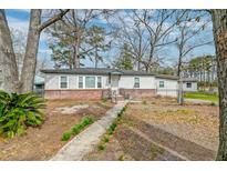 Charming single-story home with brick foundation, fenced yard, and walkway to the front door at 20 Stratton Dr, Charleston, SC 29420