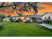 Charming single-story home with beautiful landscaping and a spacious front yard at sunset at 200 Wappoo Rd, Charleston, SC 29407