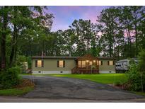 Charming single-story home with a front porch, a driveway, and surrounded by lush greenery and trees at 222 Sinclair Rd, Summerville, SC 29483