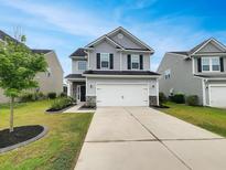 Charming two-story home with a well-manicured lawn and a two-car garage at 242 Daniels Creek Cir, Goose Creek, SC 29445