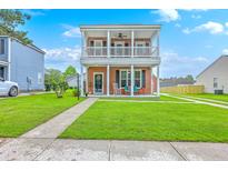 Charming two-story home featuring a double porch, a well-maintained lawn, and a welcoming walkway at 309 Harriswood Ln, Moncks Corner, SC 29461