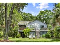 Charming two-story home featuring a lovely deck, stairs, lush greenery, and a serene setting at 3627 Holmes Dr, Johns Island, SC 29455