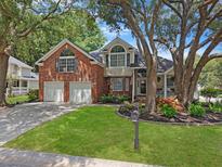 Charming two-story brick and siding home with a well-manicured lawn and mature trees at 482 Planters Trace Dr, Charleston, SC 29412