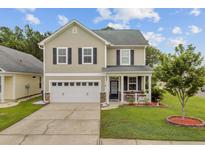Charming two-story home featuring a cozy front porch, well-maintained lawn, and attached two-car garage at 520 Crossland Dr, Moncks Corner, SC 29461
