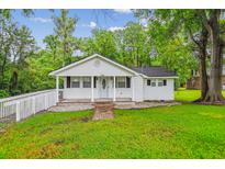 Charming single-story home boasts a well-manicured lawn, brick pathway, and a welcoming front porch at 106 N Pine St, Summerville, SC 29483