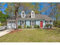 Charming single-Gathering home featuring a well-manicured front lawn, a two-car garage, and a bright red front door at 130 Shropshire St, Goose Creek, SC 29445
