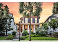 Charming two-story home with a welcoming front porch and lush landscaping at sunset at 134 Etiwan Park St, Charleston, SC 29492