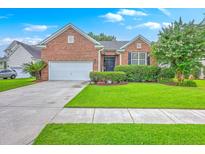 Charming brick home featuring a well-manicured lawn and a two-car garage on a sunny day at 1868 Palmetto Isle Dr, Mount Pleasant, SC 29466