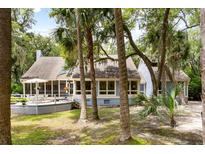 Charming coastal home featuring a screened-in porch and a spacious deck surrounded by lush greenery and mature trees at 2653 Seabrook Island Rd, Seabrook Island, SC 29455