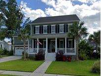Charming two-story home featuring a cozy front porch, complemented by palm trees and lush green lawn at 3739 Goodwater St, Mount Pleasant, SC 29466