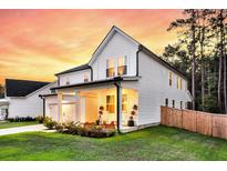 Charming two-story home with white siding, a covered porch, and lush green lawn at sunset at 69 Red Bluff St, Summerville, SC 29483