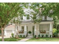 Charming two-story home with a large front porch and manicured lawn, framed by mature trees at 7053 Schooner St, Daniel Island, SC 29492