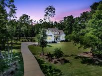Charming two-story home with landscaped yard and a long driveway at twilight at 7878 Gull Bay Dr, Awendaw, SC 29429