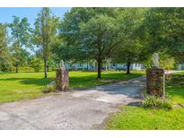 Inviting entrance featuring brick pillars with lion statues and mature trees framing the long, winding driveway at 806 Appii Rd, Moncks Corner, SC 29461