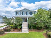 Beautiful two-story home with a welcoming front porch, attractive landscaping, and a grand staircase entrance at 1597 Rivertowne Country Club Dr, Mount Pleasant, SC 29466