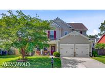 Inviting two-story home featuring a well-manicured lawn, charming front porch, and a two-car garage at 407 Glenmore Dr, Moncks Corner, SC 29461