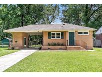 Charming brick home featuring a well-manicured lawn, green door, and a convenient covered parking area at 5172 Sterrett St, North Charleston, SC 29405