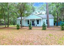 Inviting light blue home with covered porch, lush landscaping, and inviting curb appeal at 5233 Maybank Hwy, Wadmalaw Island, SC 29487