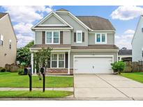 Two-story home showcasing a well-manicured lawn, gray siding, and a two-car garage under a partly cloudy sky at 535 Crossland Dr, Moncks Corner, SC 29461