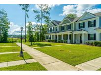 Charming townhomes feature colorful facades, well-manicured lawns, and inviting curb appeal on a sunny day at 618 Ravensridge Ln, Moncks Corner, SC 29461
