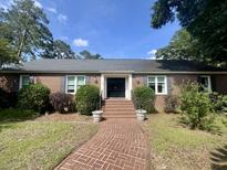 Charming brick home with a brick walkway, manicured bushes, and a double door entrance under a sunny sky at 104 Silverhill Rd, Walterboro, SC 29488