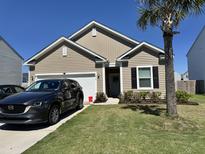 Charming one-story home featuring a well-manicured lawn, landscaped garden beds, and a driveway with a parked car at 215 Cypress Plantation Rd, Moncks Corner, SC 29461