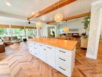 Bright and airy kitchen with a large island, wood countertops, white cabinets, and herringbone wood floors at 27 Fitzroy Dr, Charleston, SC 29414