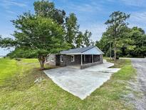 View of home with brick exterior and a covered parking area, all surrounded by lush landscaping and a concrete driveway at 4649 N U.S. Highway 52, Saint Stephen, SC 29479