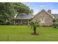 Charming brick home with a well-manicured lawn, mature trees, and a cozy front porch at 4735 W Park Pl, North Charleston, SC 29405