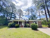 Charming brick home with a well-manicured lawn and mature trees providing shade at 710 Gadsden Loop, Walterboro, SC 29488