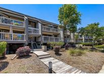 Inviting condo exterior featuring boardwalk, multiple decks, and lush landscaping at 1605 Live Oak Park, Seabrook Island, SC 29455