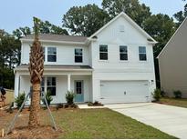 Charming two-story home with white siding, an attached two-car garage, and a neatly manicured lawn at 2018 Quiet Ibis Rd, Hanahan, SC 29410