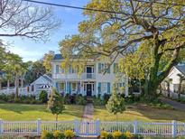 Charming two-story home with a brick walkway, white picket fence, and lush landscaping at 304 Bank St, Mount Pleasant, SC 29464