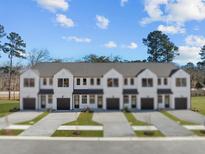 An exterior view of new construction townhomes, with manicured lawns and gray driveways at 335 Bremerton Dr, Goose Creek, SC 29445