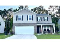 Two-story home featuring a two-car garage, gray brick accents, black shutters, and well-maintained landscaping at 619 Red Mulberry Rd, Moncks Corner, SC 29461
