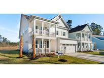 Beautiful two-story white house with a front porch, balcony, and well-manicured lawn at 735 Maynard Ln, Summerville, SC 29486