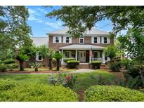 Charming brick home featuring a welcoming front porch, lush landscaping, and a well-manicured lawn at 910 Kushiwah Creek Ct, Charleston, SC 29412