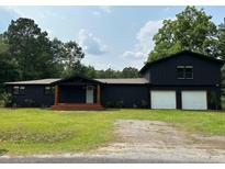 Stunning black home featuring an attached two-car garage, complemented by a lush green lawn at 1211 Lem Rd, Cordesville, SC 29434