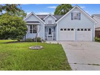 Beautiful light blue home with a well-manicured lawn and an attached two-car garage at 1245 Lakefront Drive Dr, Charleston, SC 29412