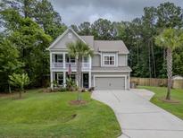 Charming two-story home with a landscaped lawn, two-car garage, and welcoming front porch at 125 Beam St, Huger, SC 29450